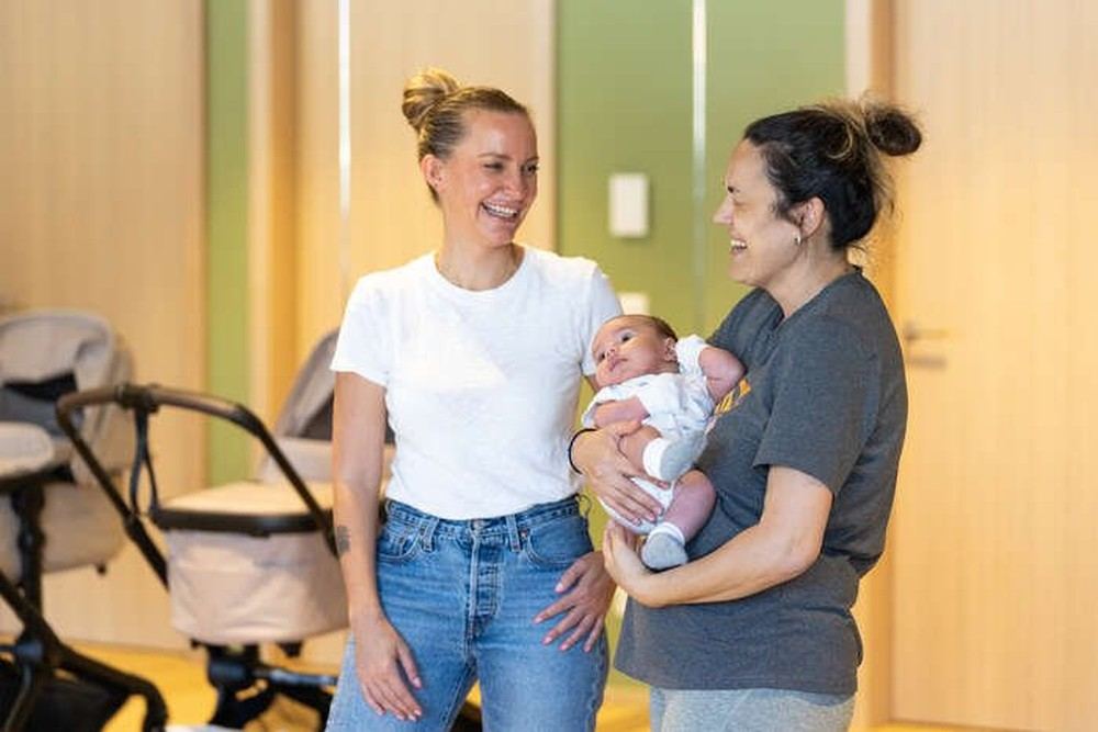 Une maman tenant son bébé dans les bras, entourée lors d'un atelier Mamæ